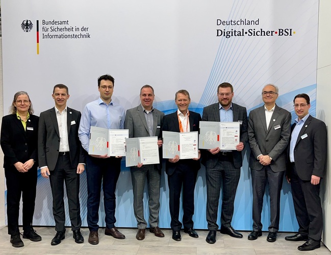 BSI-Abteilungsleiter Sandro Amendola überreicht ein Zertifikate an die Firma WEPTECH. Insgesamt acht Personen sind auf dem Bild vor einer BSI-Leinwand zu sehen. (Quelle: BSI) BSI-Abteilungsleiter Sandro Amendola überreicht ein Zertifikate an die Firma WEPTECH. Insgesamt acht Personen sind auf dem Bild vor einer BSI-Leinwand zu sehen.