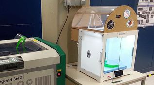 Ein 3D-Drucker, in dem ein Gesichtsschutz liegt. Ein weiterer Gesichtsschutz liegt daneben auf einem Gerät. (Quelle: BSI) Ein 3D-Drucker, in dem ein Gesichtsschutz liegt. Ein weiterer Gesichtsschutz liegt daneben auf einem Gerät.