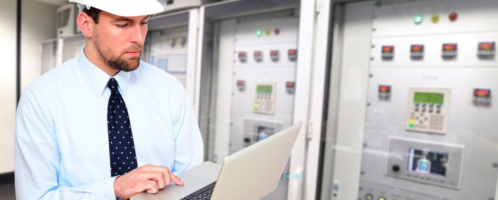 Techniker mit Laptop vor Steuerungsanlage (Quelle: © industrieblick / Fotolia.com) Techniker mit Laptop vor Steuerungsanlage