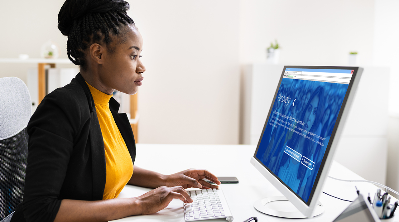 Eine Frau schaut auf ihren Bildschirm auf dem Schreibtisch, der eine blaue Fehlermeldung anzeigt. (Quelle: Adobe Stock (c) Wetzka, Andrey-Popov ) Eine Frau schaut auf ihren Bildschirm auf dem Schreibtisch, der eine blaue Fehlermeldung anzeigt.