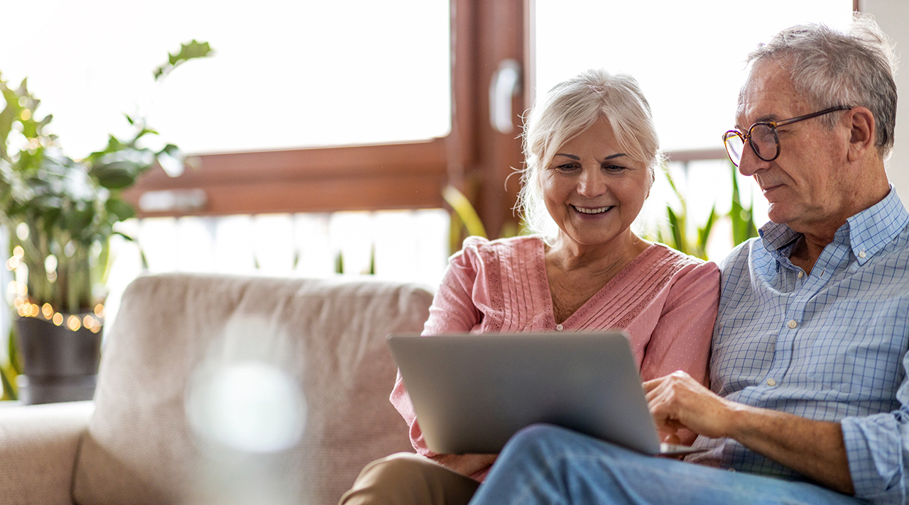 Eine Seniorin und ein Senior sitze nebeneinander auf der Couch und schauen auf einen Laptop. (Quelle: © pikselstock / Adobe Stock) Eine Seniorin und ein Senior sitze nebeneinander auf der Couch und schauen auf einen Laptop.